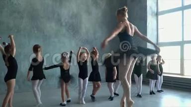 可爱的女孩学跳舞。 穿着黑色舞服训练的小芭蕾舞女。 芭蕾舞学校。 双腿合拢...
